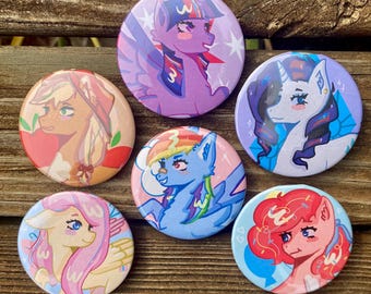 Può includere: Una collezione di sei spille rotonde con illustrazioni di pony dei cartoni animati colorati. Ogni spilla presenta un personaggio pony diverso con design e schemi di colori unici, su uno sfondo di legno.
