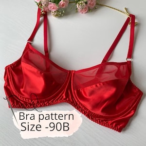 Peut inclure: Un soutien-gorge rouge en satin avec des panneaux en résille transparente. Le soutien-gorge a des bretelles réglables et un maintien avec armatures. Le texte "Bra pattern Size -90B" est visible.