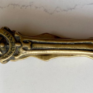 May include: A vintage brass pocket knife with ornate detailing. The knife features a decorative handle and the text "WINCHESTER STEEL". The overall design is reminiscent of antique craftsmanship, with a focus on durability and style.