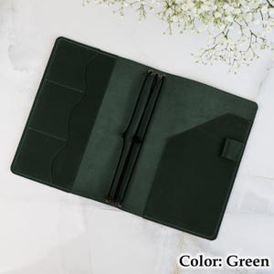 May include: Open, dark green leather journal cover with multiple pockets and elastic closures. The cover is shown open, revealing interior pockets and elastic bands. The text "Color: Green" is visible in the bottom right corner.