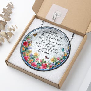 May include: A round, stained-glass retirement gift with a floral border and butterflies. The text reads "Never Underestimate The Difference You've Made and The Lives You've Touched! Happy Retirement Brenda."