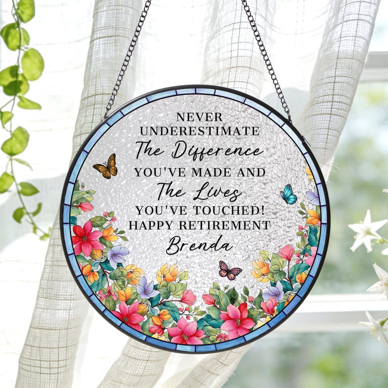 May include: Round stained glass retirement gift with a floral border and butterflies. The text reads "NEVER UNDERESTIMATE The Difference YOU'VE MADE AND The Lives YOU'VE TOUCHED! HAPPY RETIREMENT Brenda."