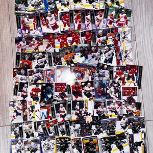May include: A collection of hockey trading cards, showing players in action. The cards feature team logos and player names, with action shots and portraits. The cards are arranged in a scattered, overlapping pattern.