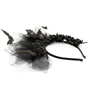 May include: A black Halloween headband featuring black roses, bat cutouts, and a tulle accent. The headband is made of a thin, black plastic and is designed to be worn on the head. The overall design is gothic and spooky.