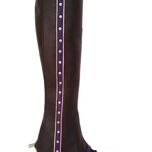 May include: A brown leather riding half chap with a purple top and accents. The chap features a vertical stripe with small, clear rhinestones and gold trim. The chap is worn over a brown leather riding boot.