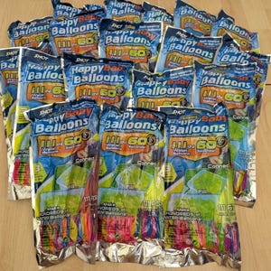 May include: Multiple packages of "Happy Baby Balloons" are displayed, each containing 111 pieces. The packaging is primarily blue, yellow, and silver, with text indicating the balloons fill in 60 seconds. The image shows a collection of water balloons.