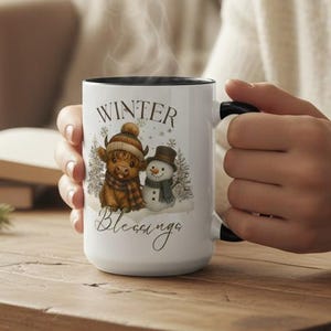 May include: A white ceramic mug with a black interior and handle, featuring a winter-themed illustration. The design includes a cow and a snowman wearing winter accessories, with the words "Winter Blessings" printed on the mug.