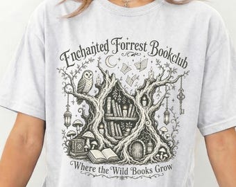 May include: A light gray t-shirt featuring a black ink-style graphic of a tree shaped like a library with shelves of books, an owl, mushrooms, lanterns, and the text "Enchanted Forrest Bookclub" and "Where the Wild Books Grow" printed on the front.