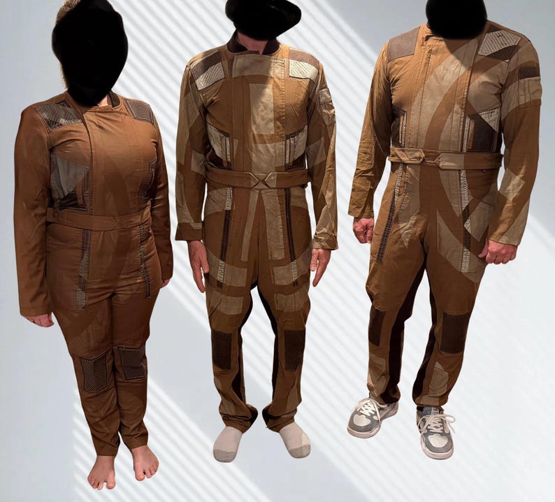 May include: Three brown jumpsuits featuring a patchwork design with varying shades of tan and dark brown fabric. Each garment includes a structured collar, long sleeves, a fitted waist belt, and reinforced paneling on the shoulders and legs.