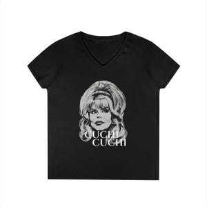 May include: Black V-neck t-shirt featuring a black and white graphic of a woman with large hair and the text "OUCHI CUCHI" in white. The shirt is made of a soft material.
