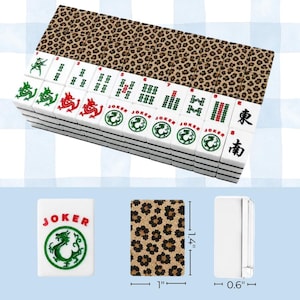 May include: A set of white mahjong tiles with leopard print backs. The tiles feature green and red dragon symbols, numbers 1 through 9, Joker text with dragon icons, and East and South characters. Individual tiles measure 1.4 inches by 1 inch by 0.6 inches.