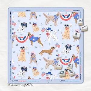 Puede incluir: Una alfombrilla de mahjong azul claro con un patr&oacute;n repetitivo de perros con accesorios patri&oacute;ticos, banderas estadounidenses y estrellas. El borde incluye el texto DRAGONS, JOKERS y BAMS. Varias fichas de mahjong blancas est&aacute;n esparcidas.