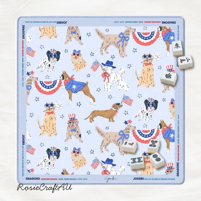 Puede incluir: Una alfombrilla de mahjong azul claro con un patr&oacute;n repetitivo de perros con accesorios patri&oacute;ticos, banderas estadounidenses y estrellas. El borde incluye el texto DRAGONS, JOKERS y BAMS. Varias fichas de mahjong blancas est&aacute;n esparcidas.