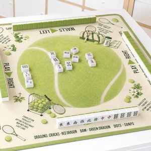 May include: A square Mahjong mat featuring a tennis ball graphic in the center, surrounded by tennis-themed illustrations including rackets, balls, and a bag. The mat includes printed text instructions and rows of white Mahjong tiles with green backs.