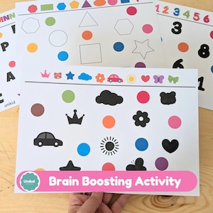 May include: Educational activity sheets with colorful shapes, numbers, and letters. The sheets feature various shapes, dots, and illustrations of a car, crown, and sun. The text "Brain Boosting Activity" is displayed on a pink banner.
