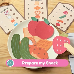 May include: A children's educational game with paper cutouts of food items, including apples, cucumbers, and waffles, arranged on a plate. The game includes snack menu cards and the text "Prepare my Snack".