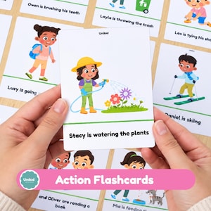 Può includere: Una flashcard educativa bianca con un'illustrazione a cartoni animati di una persona con cappello giallo e salopette verde che annaffia fiori colorati con un tubo blu. Il testo Stacy is watering the plants è stampato in nero in basso.