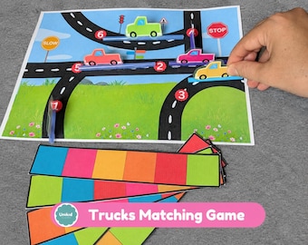 May include: A Trucks Matching Game featuring a printed road map with numbered red circles, traffic signs, and colorful truck cutouts. The set includes several rectangular cards divided into six vibrant, multi-colored segments.