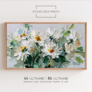 以下が含まれることがあります： 白い花、黄色の中心、緑の葉が描かれた額入りの花の絵。アートワークには「STUDIO VIEW PRINTS」と「4k ULTRAHD | 8k ULTRAHD PREMIUM HIGH DEFINITION FRAME TV ART」と書かれています。フレームは明るい茶色です。