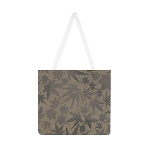 May include: A tote bag featuring a repeating pattern of cannabis leaves in grey and brown tones. It has white handles and a rectangular design.