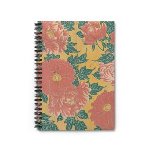 以下が含まれることがあります： 花柄のデザインが施されたスパイラル綴じノート。表紙には、黄色の背景に、黄色の中心と緑の葉を持つ大きなピンク色の牡丹の花のパターンが表示されています。ノートの綴じは黒です。