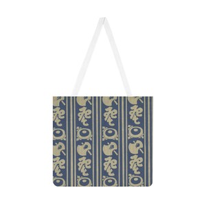 May include: A tote bag with a repeating pattern of stylized shapes in beige and navy blue. The bag has a white handle and a rectangular body. The pattern is arranged in vertical stripes, creating a visually appealing design.
