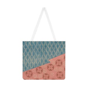 Könnte beinhalten: Eine Tragetasche mit geometrischem Design. Die obere Hälfte der Tasche zeigt ein tealfarbenes Muster mit weißen Punkten und wellenförmigen Linien. Die untere Hälfte ist korallenfarben mit einem kreisförmigen Muster. Die Tasche hat weiße Träger.