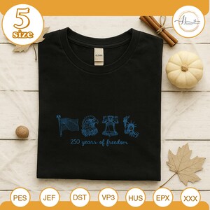 Może przedstawiać: Czarny t-shirt z okrągłym dekoltem z niebieskim nadrukiem graficznym przedstawiającym amerykańską flagę, orła, Dzwon Wolności i Statuę Wolności. Pod grafiką znajduje się napis "250 years of freedom".