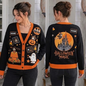 May include: A black button-down cardigan with orange trim featuring Halloween-themed graphics of Mickey Mouse, pumpkins, ghosts, and a castle. The back displays a large castle graphic with the text HALLOWEEN MAGIC and a customizable NAME patch.