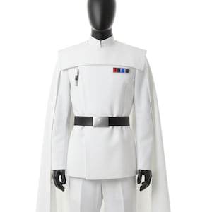 Może przedstawiać: Biały kostium z pasującą peleryną, spodniami i kurtką. Kurtka ma czarny pasek ze srebrną klamrą, małą kieszeń z długopisem i odznakę z czerwonymi, niebieskimi i białymi paskami.