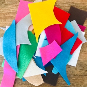 May include: A collection of assorted felt fabric scraps in various shapes and sizes. The pieces feature a vibrant color palette including yellow, red, pink, blue, green, white, gray, brown, and beige, showcasing diverse textures and cut edges.