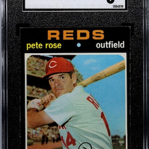 May include: A baseball card featuring Pete Rose in a Cincinnati Reds uniform, holding a bat. The card is graded EX 5 by SGC. The card reads "1971 TOPPS #100 PETE ROSE" and "REDS outfield". The card is encased in a black holder.