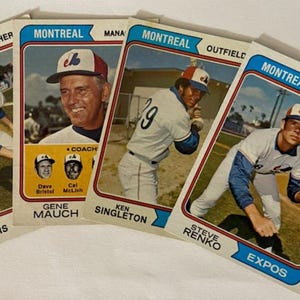 May include: Four vintage Montreal Expos baseball cards. The cards feature players and coaches, including Steve Rogers, Gene Mauch, Ken Singleton, and Steve Renko. The cards have a white border and the team name is in blue.