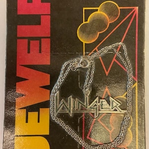 May include: A silver-colored necklace with the name "WINGER" in a stylized font, displayed on a black and red card. The card reads "JEWELRY" in large yellow letters and "Great Southern Company". The necklace is 14KT. Gold or Silver Nickle Overlayed.