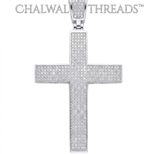 May include: A silver-toned cross pendant fully encrusted with small, clear, sparkling stones. The bail is also covered in matching stones. The text CHALWAL THREADS™ is visible in the upper portion of the image, positioned behind the pendant.