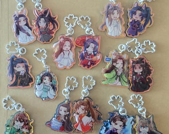 Op de afbeelding: Een verzameling anime-stijl acryl sleutelhangers met verschillende personages in kleurrijke outfits. Elke sleutelhanger heeft een zilverkleurige ketting en een decoratieve klavervormige sluiting. De personages hebben verschillende kapsels en uitdrukkingen, sommige dragen dierenoren.