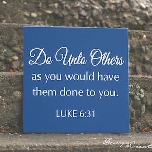May include: A blue wooden sign with white text that reads "Do Unto Others as you would have them done to you. LUKE 6:31".