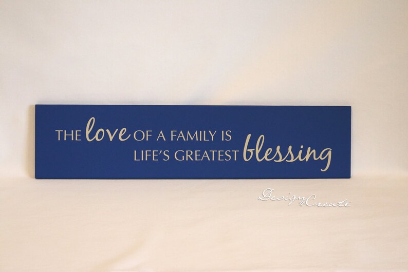 May include: A blue wooden sign with the text "The love of a family is life's greatest blessing" in white lettering.