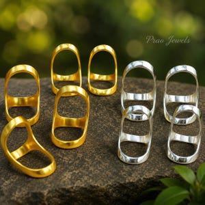 May include: A collection of open-frame rings featuring a smooth, rounded design. The set includes four gold-toned rings and four silver-toned rings, all with a polished finish. The text Prao Jewels is visible in the upper right corner of the image.