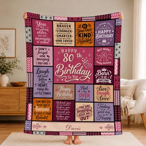 May include: A rectangular throw blanket featuring a patchwork design with various shades of pink, purple, orange, and black. The blanket displays multiple inspirational birthday messages and the text Happy 80th Birthday To You and the name Davis.