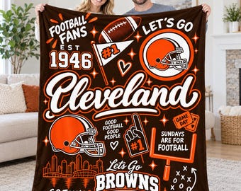 May include: A brown fleece blanket featuring orange and white graphics of football helmets, a football, a goalpost, and the text "Football Fans Est 1946", "Cleveland", "Let's Go Browns", "Sundays Are For Football", and "Good Football Good People".