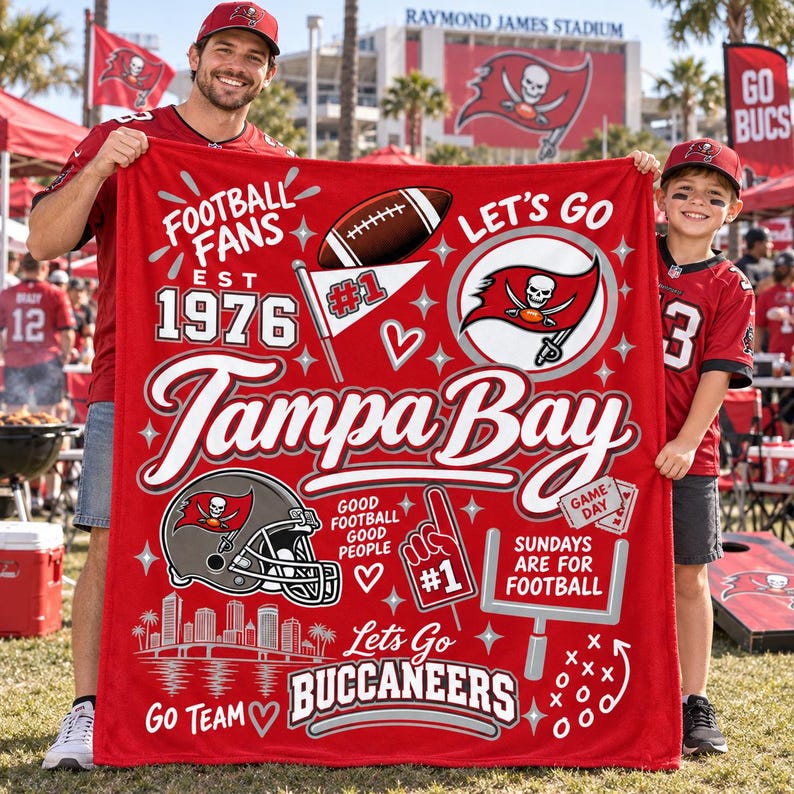 May include: A red fleece blanket featuring Tampa Bay Buccaneers graphics, including a football, a helmet, a foam finger, a goalpost, the text 'Tampa Bay', 'Football Fans Est 1976', 'Let's Go', 'Sundays Are For Football', and 'Let's Go Buccaneers'.