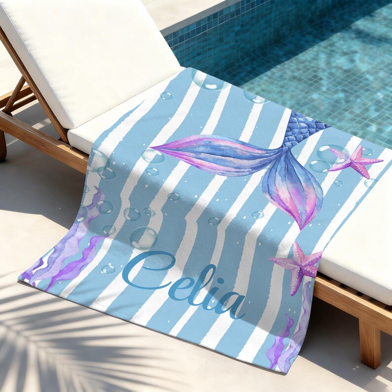 May include: A blue and white striped beach towel featuring a watercolor mermaid tail in shades of blue and purple. The towel includes the name "Celia" in script and starfish accents.