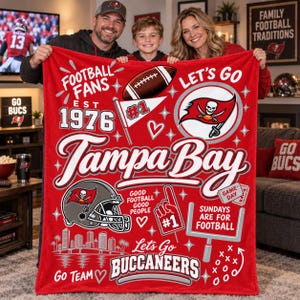 May include: A red fleece blanket featuring Tampa Bay Buccaneers graphics, including a football, a team logo, a helmet, a goalpost, and text such as "Football Fans Est 1976," "Tampa Bay," "Good Football Good People," and "Sundays Are For Football."