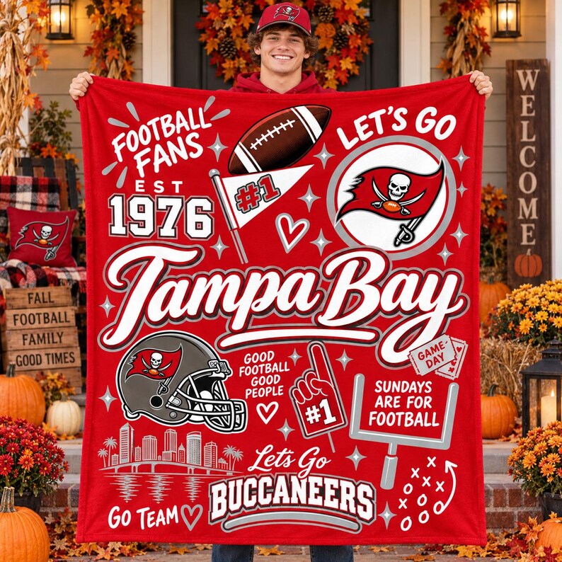 May include: A red fleece blanket featuring Tampa Bay Buccaneers football graphics, including a helmet, a football, a goalpost, the text 'Tampa Bay', 'Est 1976', 'Football Fans', 'Let's Go', 'Sundays Are For Football', and 'Go Team'.