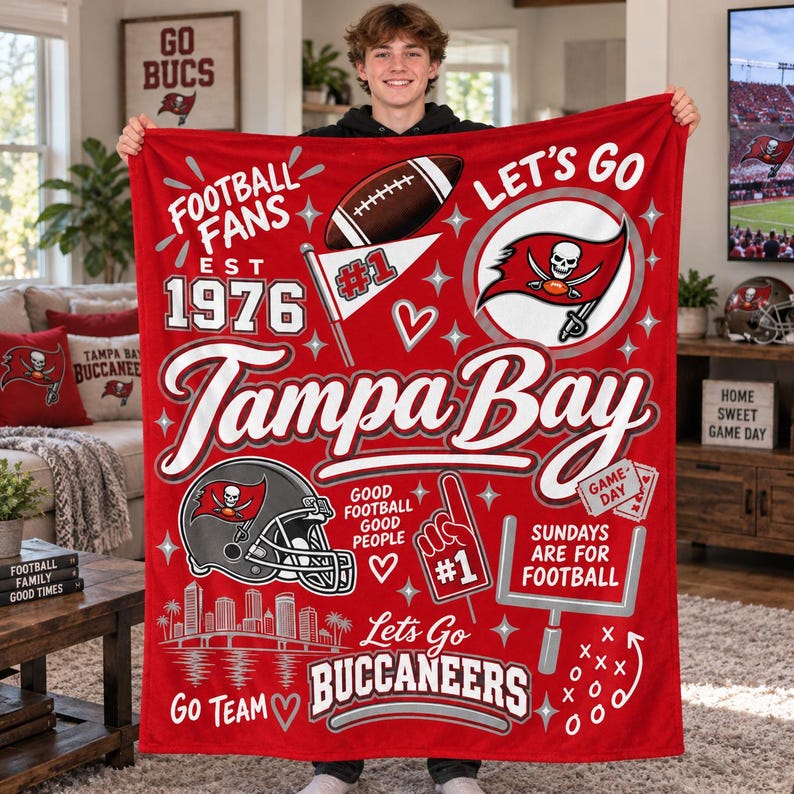 May include: A red fleece blanket featuring Tampa Bay Buccaneers graphics, including a football, a skull logo, a helmet, a goalpost, and text reading Football Fans Est 1976, Tampa Bay, Good Football Good People, and Sundays Are For Football.