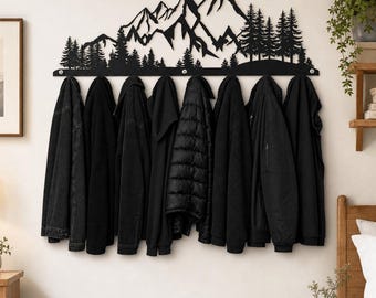 Puede incluir: Un perchero de pared de metal negro con una silueta cortada con láser de una cadena montañosa y pinos. El perchero tiene varios ganchos de color plateado en el borde inferior, que sostienen varias chaquetas y abrigos negros de diversas texturas.