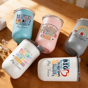 May include: An assortment of insulated tumblers in various colors, including blue, pink, gray, and white. Each tumbler features a design with text and graphics related to teaching, such as pencils, rainbows, and the phrase "It takes a big heart to teach little minds."