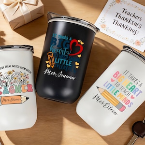 May include: Three insulated tumblers with teacher-themed designs. One white tumbler has the text "TEACHER" and a pencil graphic. A black tumbler has the text "It takes a BIG heart" and a red heart graphic. A white tumbler has the text "It takes a BIG heart to teach little minds."
