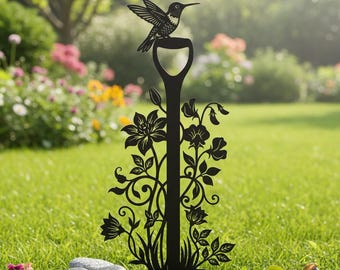 Può includere: Paletto da giardino in metallo nero con un colibrì appollaiato su un manico a forma di pala. Il paletto è adornato con ritagli floreali e di vite, aggiungendo un tocco decorativo a qualsiasi spazio esterno. Il colibrì ha le ali spiegate.